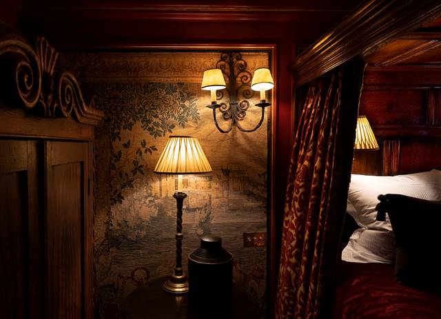 Antique lamp, wall panels and gothic velvet drapery on four poster bed in The Armoury hotel suite, in Edinburgh UK